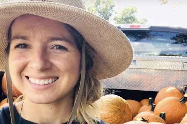 Photo of Krystle Owen in front of truck bed filled with pumpkins